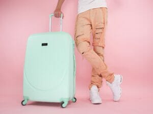 Photo by Kindel Media: https://www.pexels.com/photo/person-wearing-brown-pants-standing-beside-a-green-suitcase-8212233/