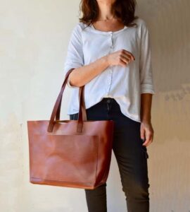 young modern girl holding dark tan fossil bag 